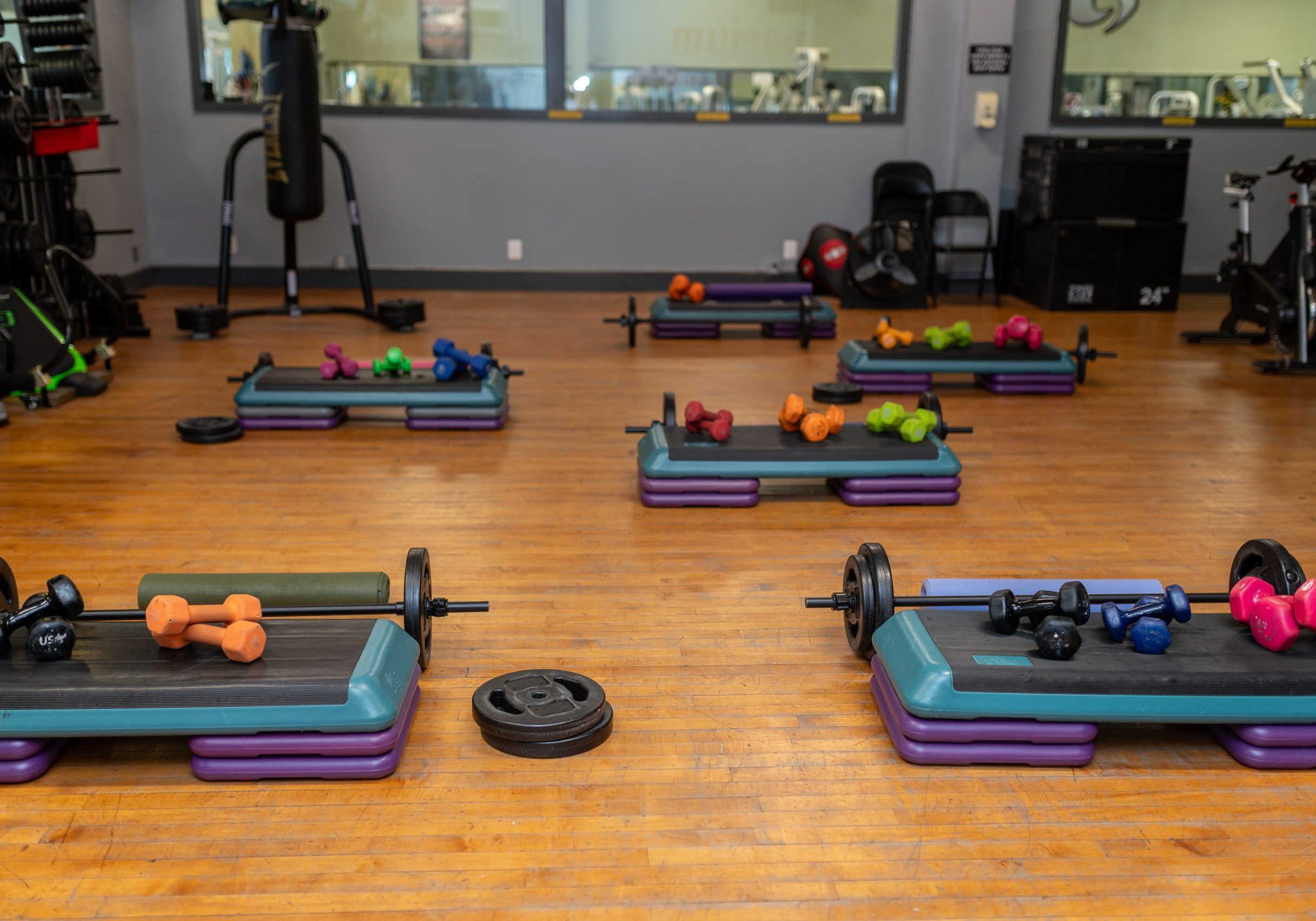 Dumbbell, bars with plates, steps and risers set up for various group fitness classes.